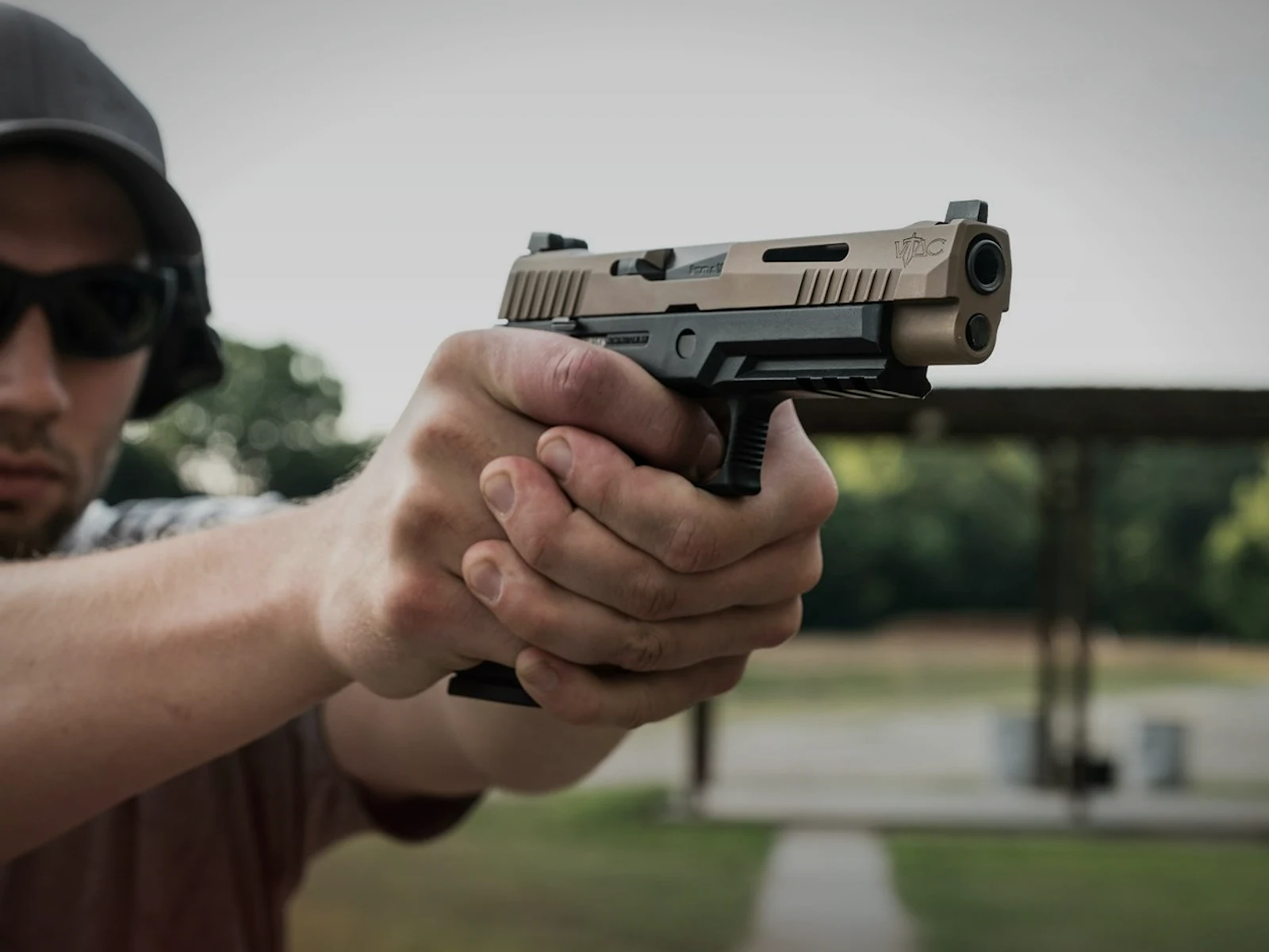 Shooter aiming a semi-automatic handgun at an outdoor range