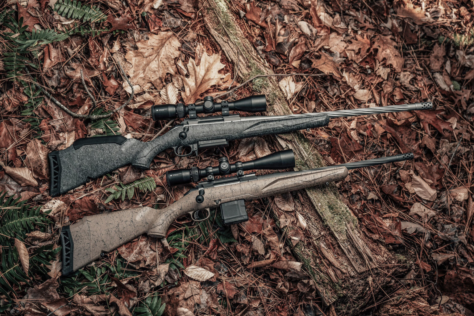 Two Ruger American Gen II bolt-action rifles on a forest floor